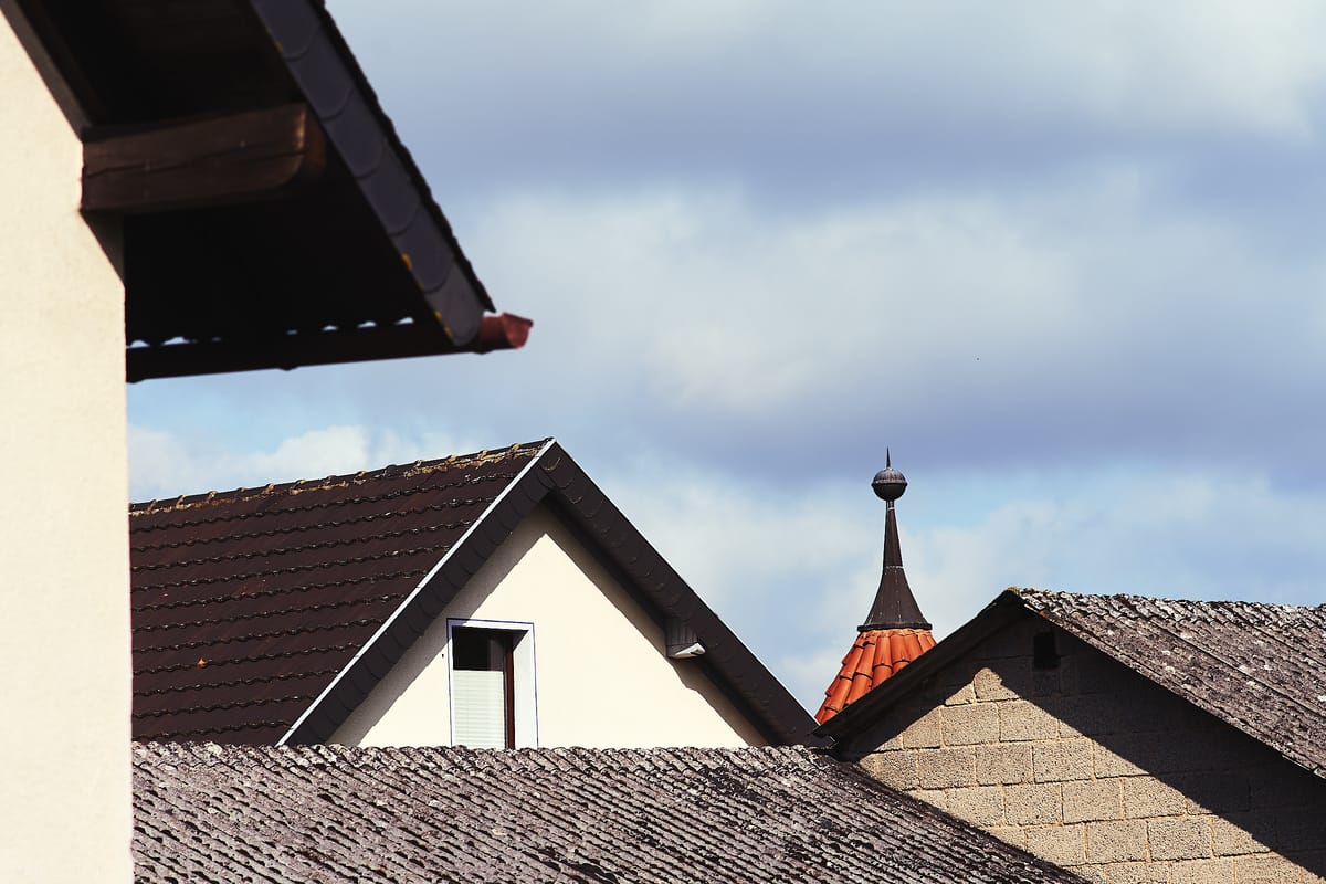 Image of four kinds of roofs against a stormy sky.