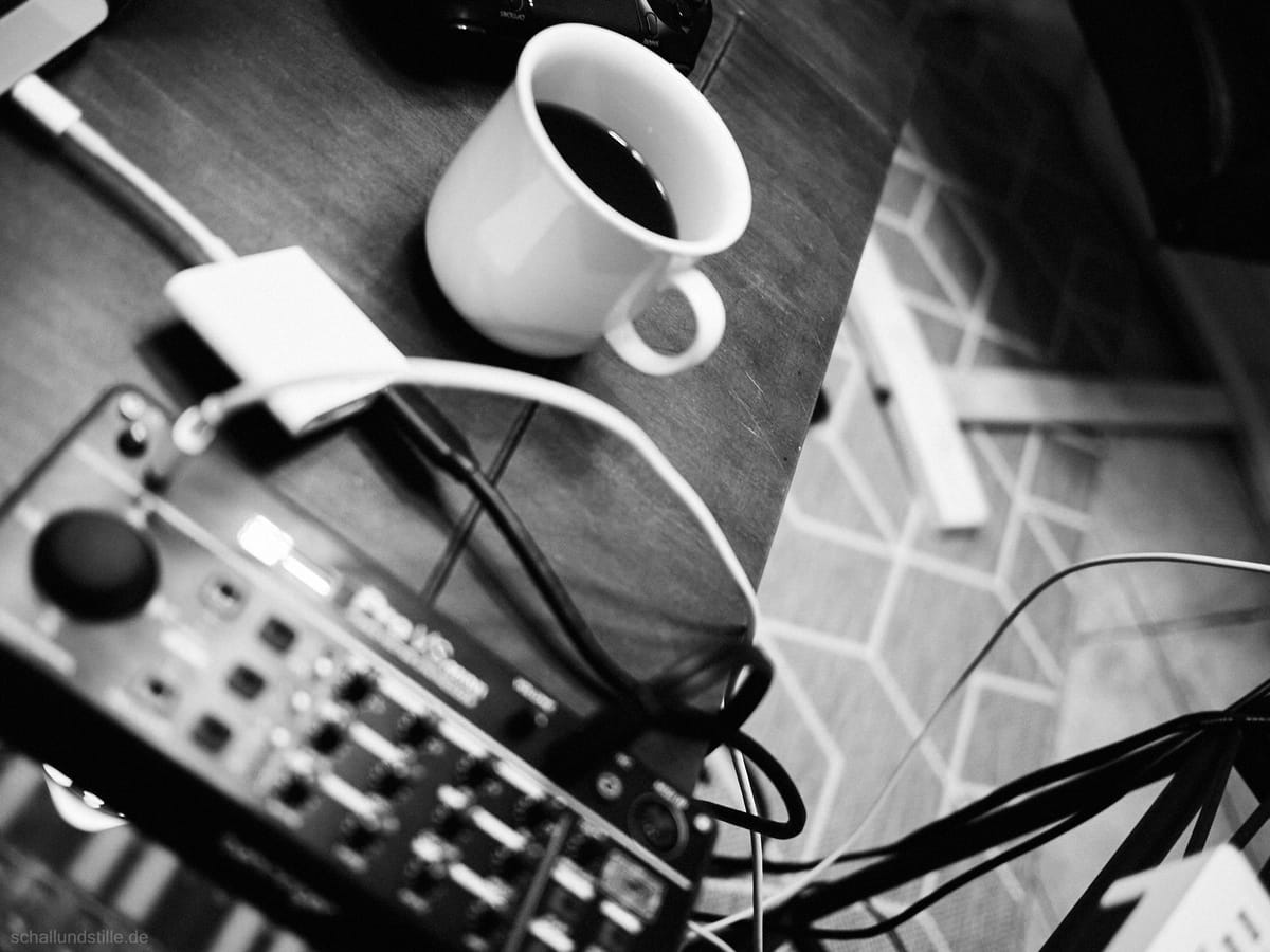 black and white picture of a Behringer Pro VS Mini synthesizer (unsharp) in the foreground and a cup of coffee in the backgro