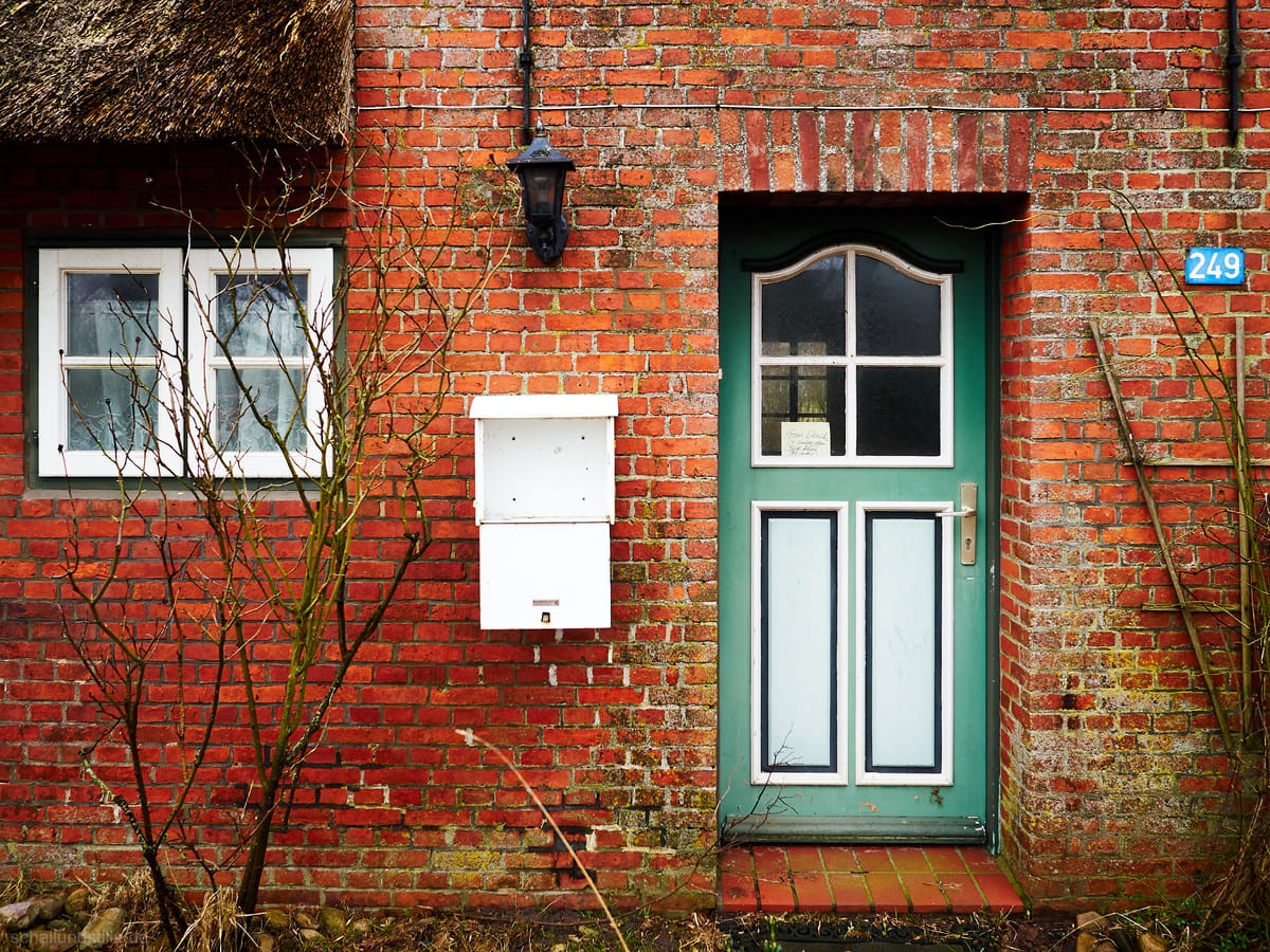 An abandoned North Frresian home. in the door there is a notice saying "Frau Wenske ist umgezogen. Bitte keine Post mehr" ("M