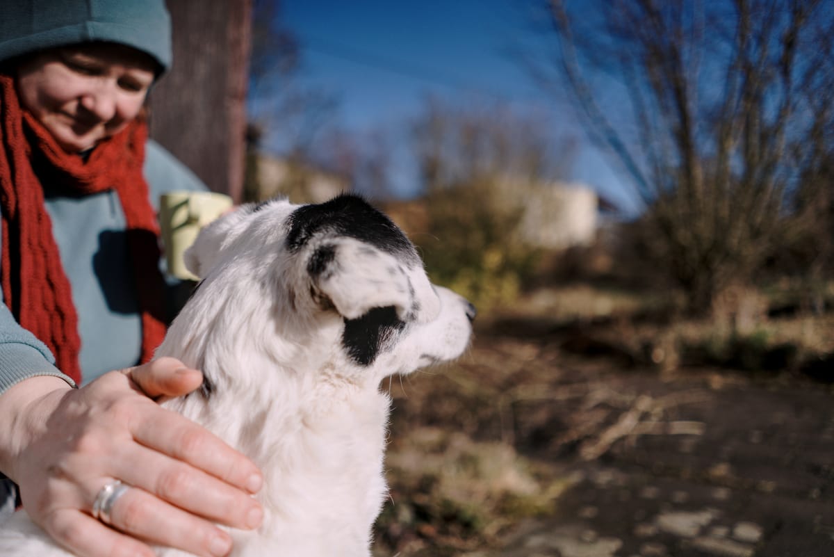 A woman with a shawl gently stroking a dog sitting next to her