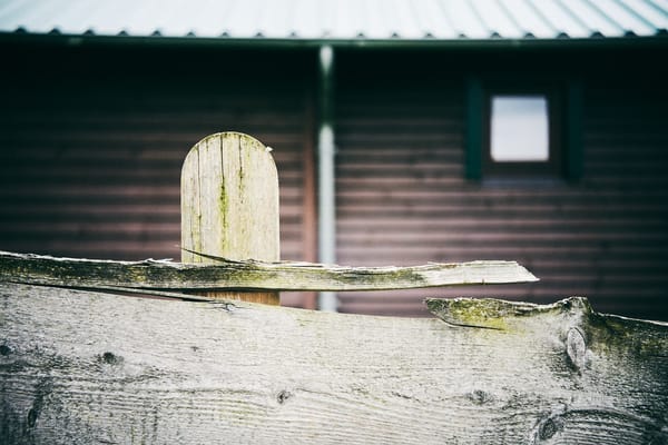 A wooden building behind a wooden fence.