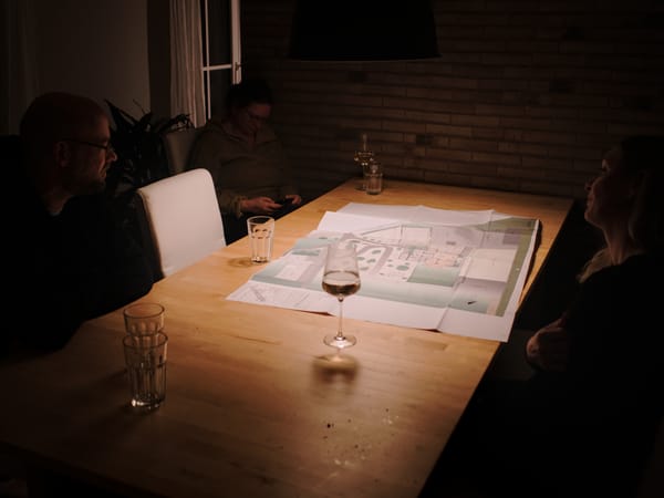 several people sitting around a wooden table with a plan on it