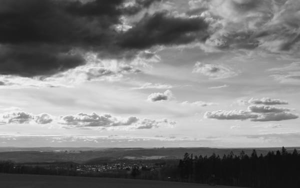 A cloudly black and white landscape. The Wachtberg Radom can be seen near the horizon.