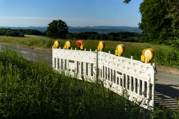 a road barrier with five yellow lights and one red light beside a country lane